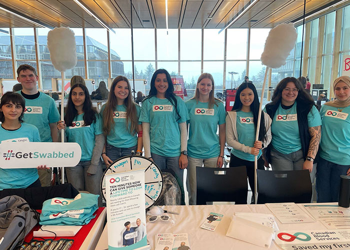 Group of students wearing blue Canadian Blood Services t-shirts standing in a horizontal line