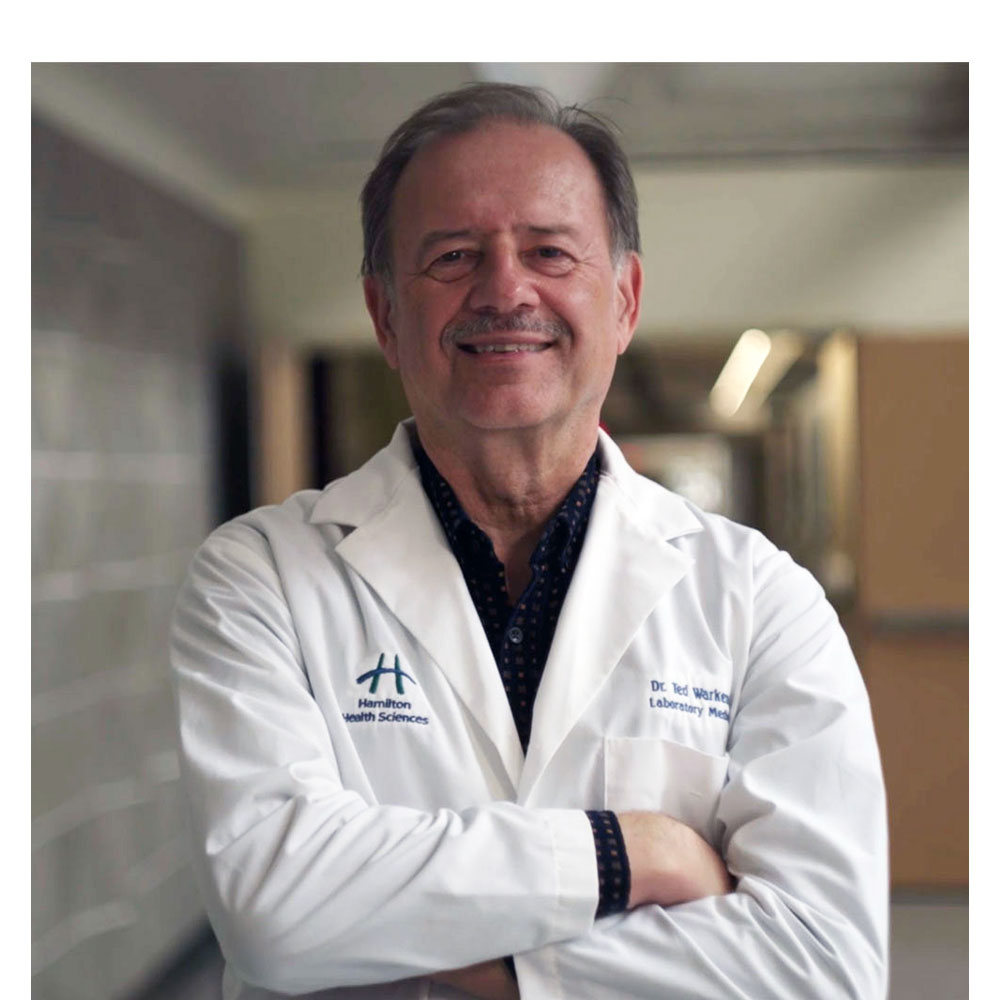 Dr. Theodore (Ted) Warkentin wearing a white lab coat with arms crossed