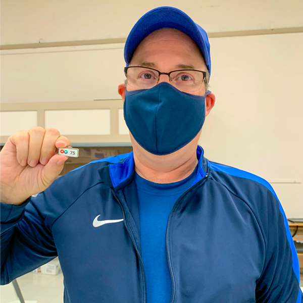 Image of Geoff Van Geem holding a pin while wearing a mask