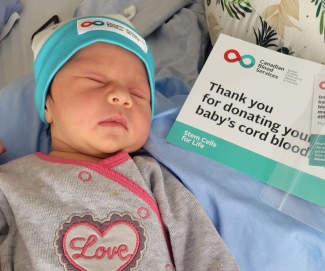 Baby wearing cord blood donor hat with cord blood donation sign