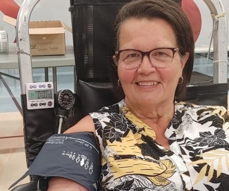 Blood donor in donation chair with pressure cuff visible