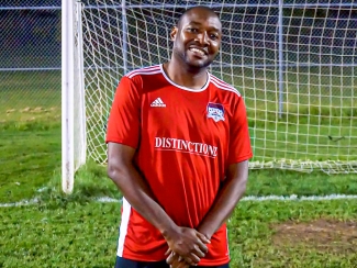 Canadian blood services manager in soccer uniform in front of soccer net