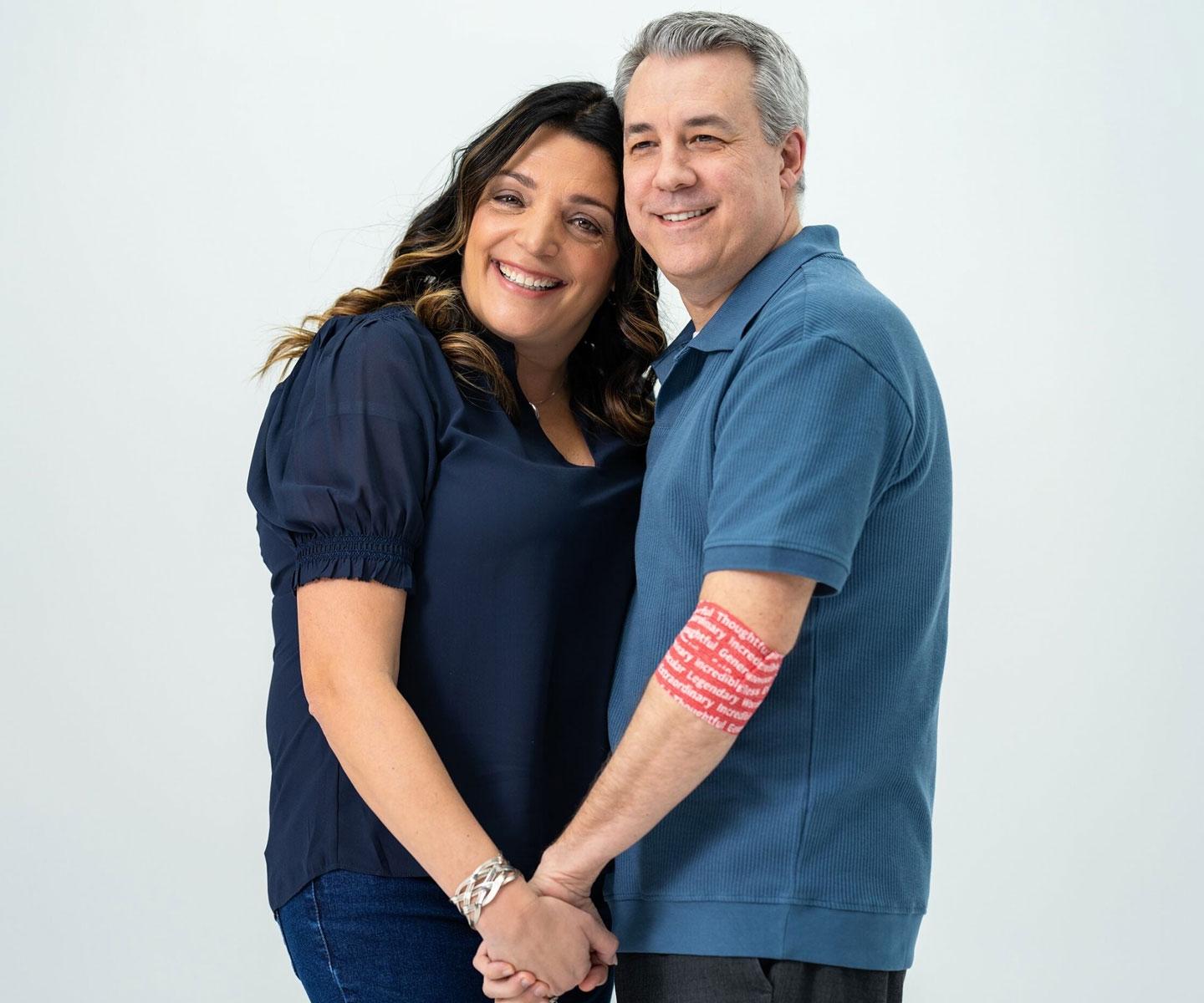 Une receveuse de sang main dans la main avec son mari, qui porte un bandage au bras en tant que donneur de sang