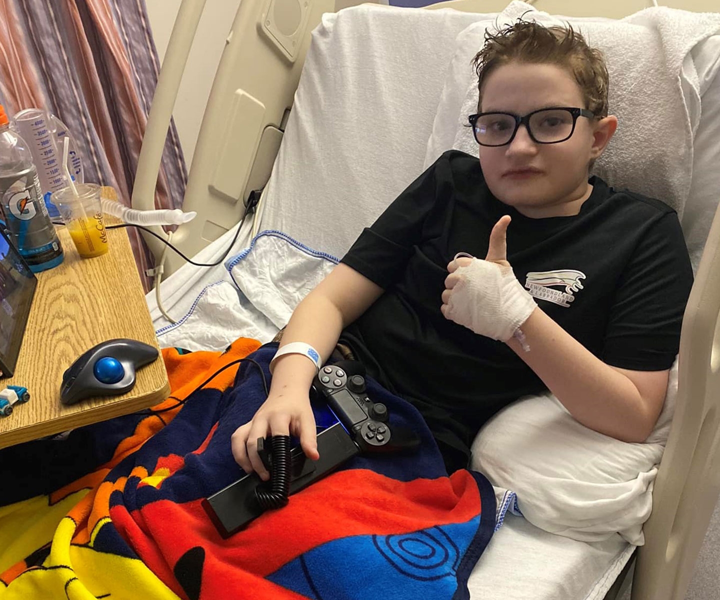 Pediatric patient in hospital bed giving a ‘thumbs up’