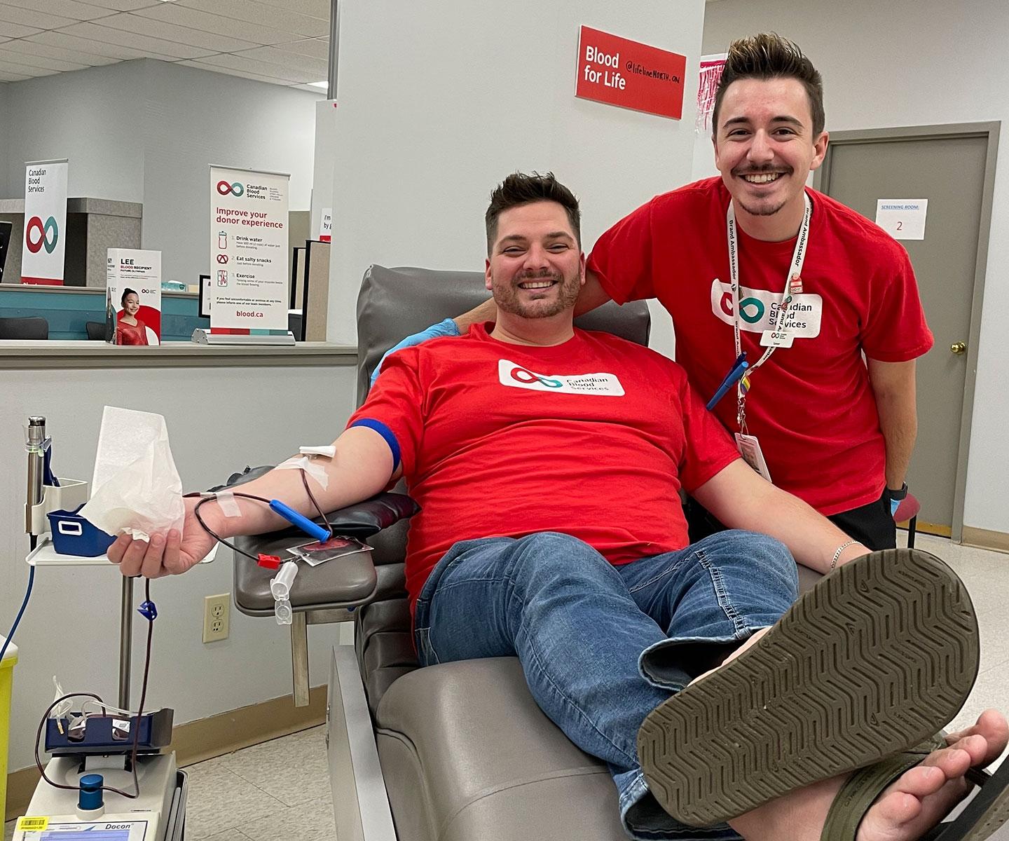 Man donating blood with partner smiling at his side