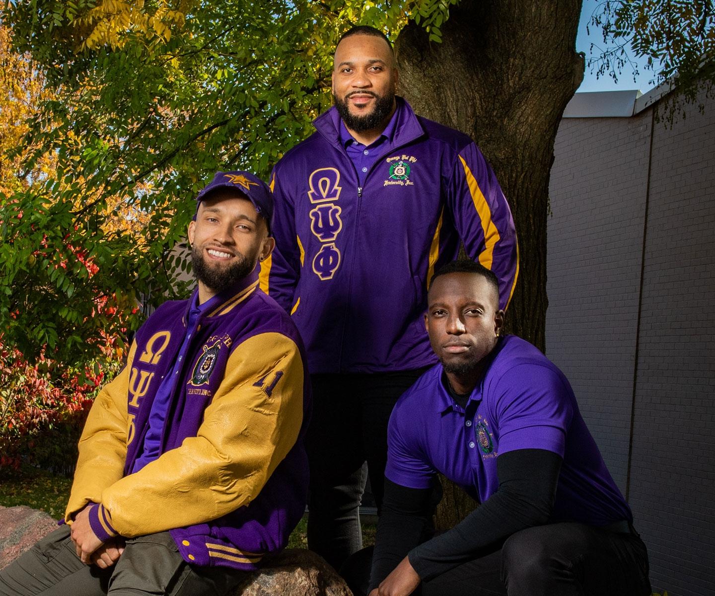 Three members of Lambda Mu Mu together outdoors in fraternity clothing