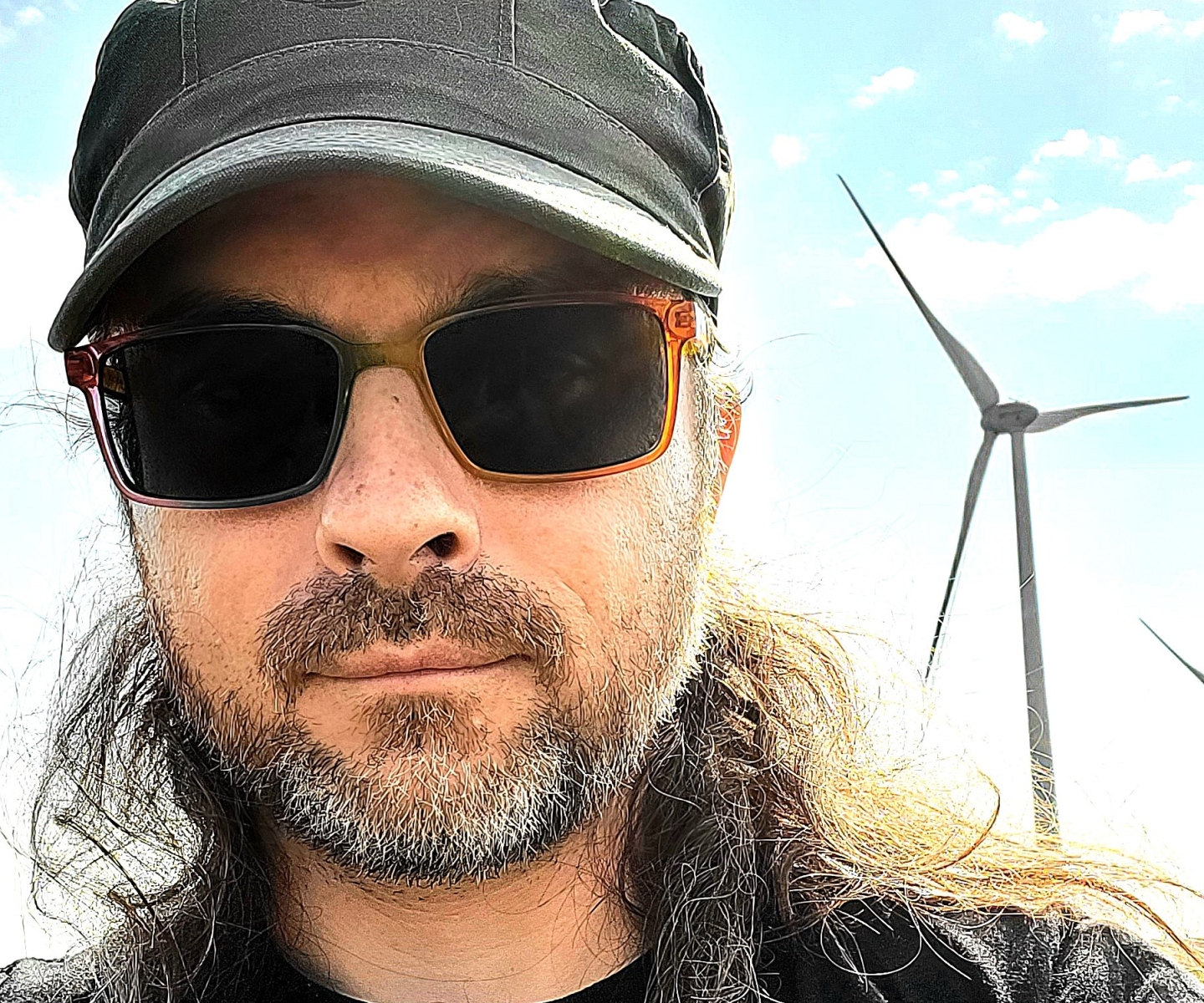 Blood donor in hat in front of wind turbine