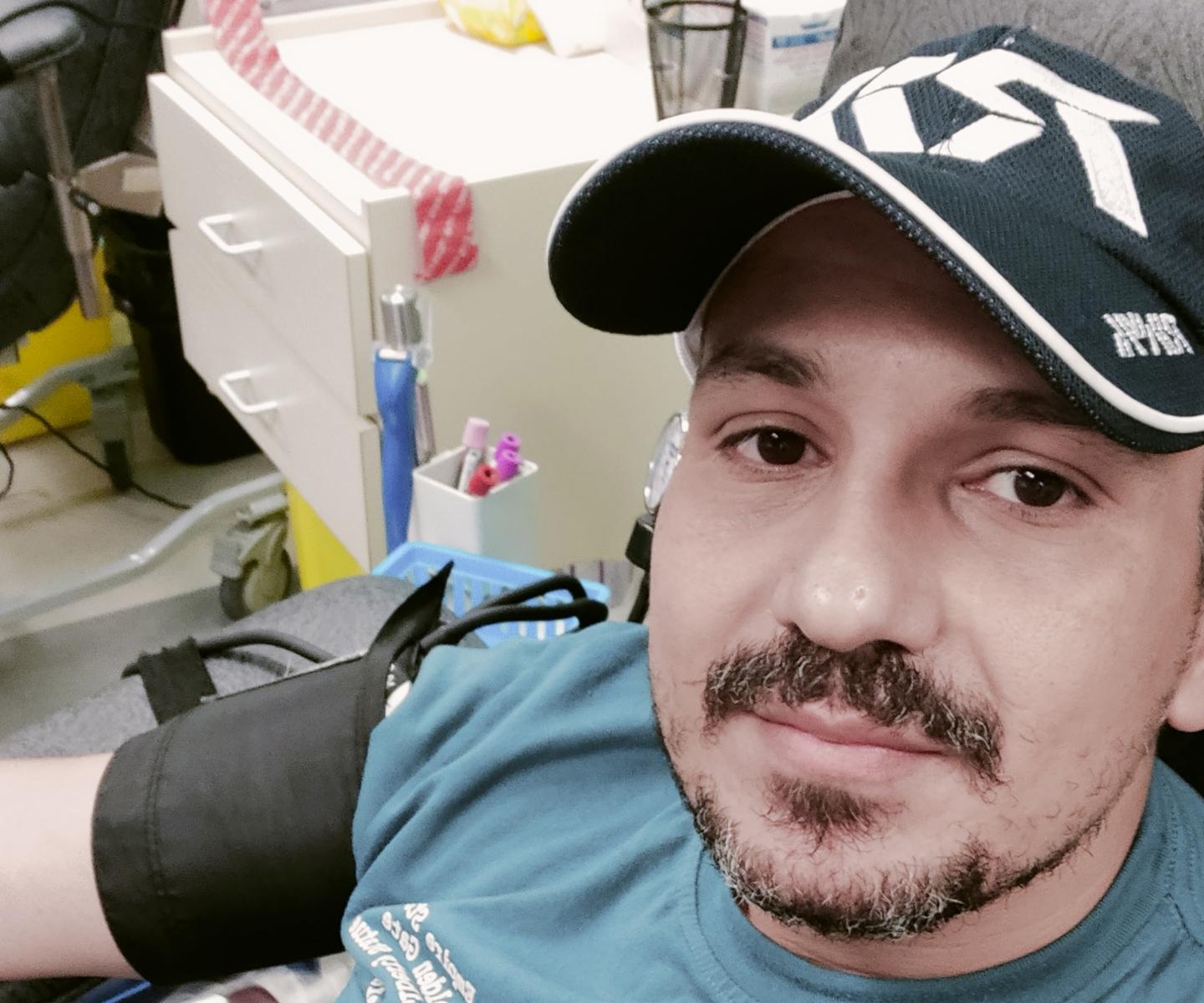 Man in ball cap donating O-negative blood
