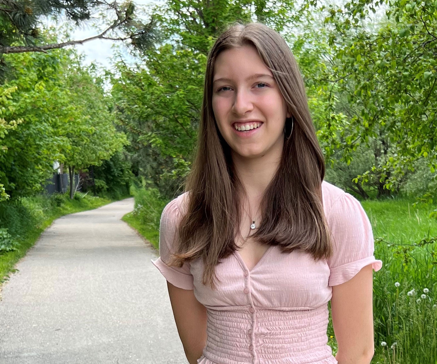 A young plasma recipient standing outside in nature, smiling