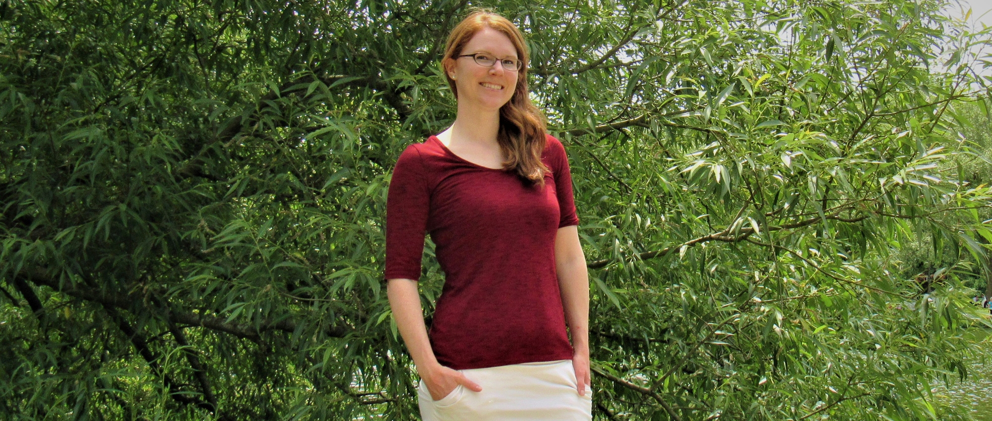 Stem cell donor Rachel Van Pelt stands in front of a green tree by a lake.