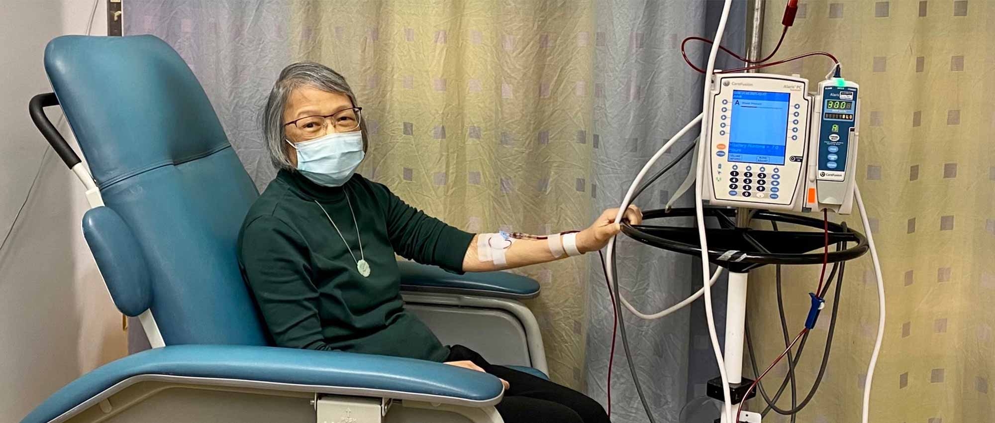 A woman in a mask receiving a blood transfusion