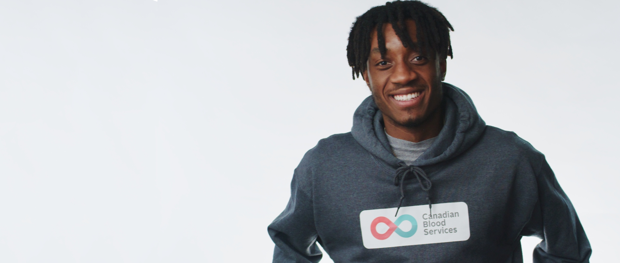 Hockey Gives Blood Player Ambassador Zack Stringer smiles in a Canadian Blood Services pullover hoodie