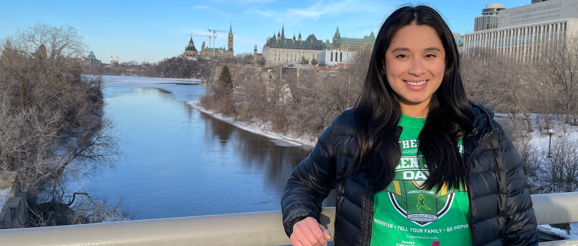 A woman in a green shirt stands on a bridge in Ottawa 