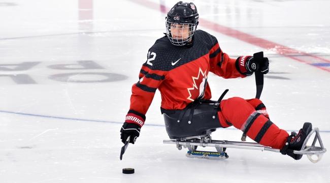 Para-hockey player moving stick toward puck on the ice