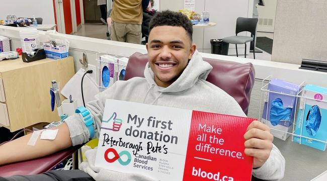 Blood donor in donor chair holding a “My first donation” sign