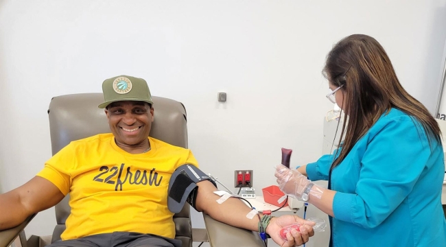 Rare blood donor sitting in chair as phlebotomist draws his blood.