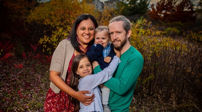 family of four hugging outdoors 