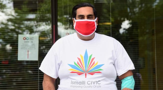 Imran, a young man with a mask on and an Ismaili Civic tee