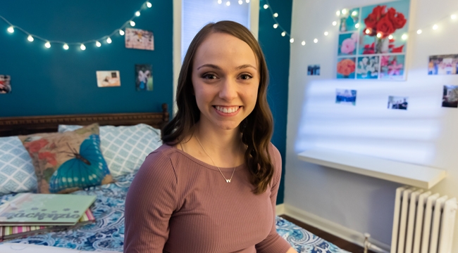 Image of Mackenzie Curran sitting on her bed in her bedroom